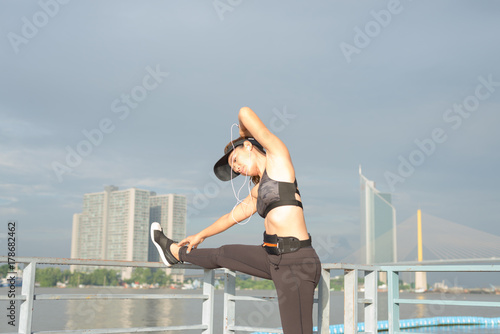 asian woman doing stretching exercises outdoors along city sidewalk