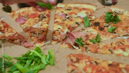 female hands sprinkle the pizza with herbs photo