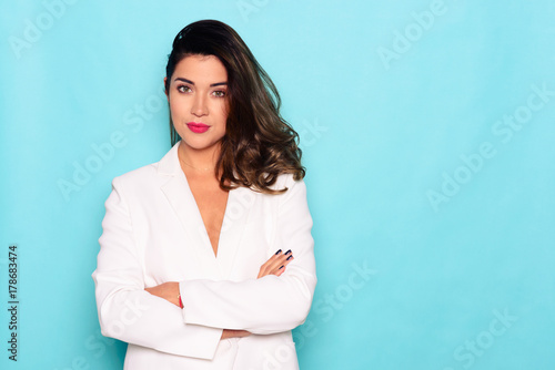 Beautiful fashion female with arms crossed. Studio shot on blue background. photo