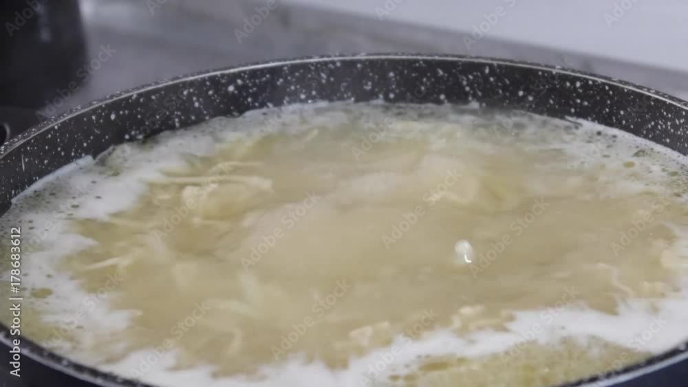 Housewife cooks noodles in a saucepan Housewife cooks noodles in a saucepan