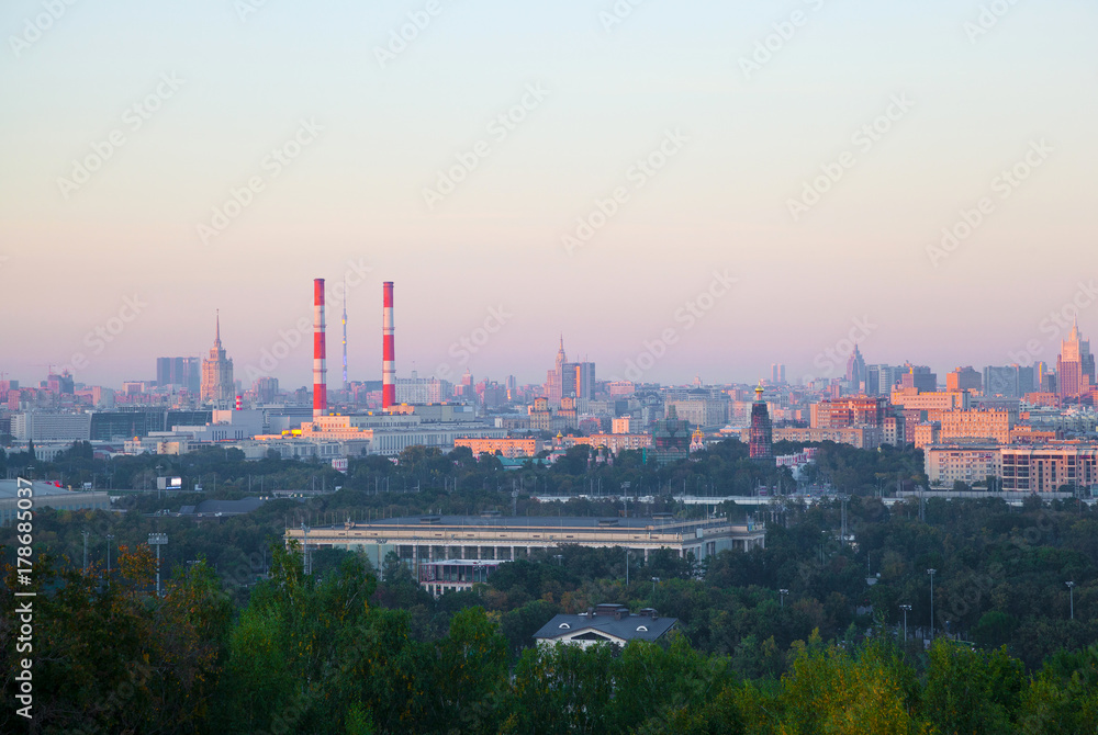 the skyline of a large city at sunset. Residential houses, industrial pipe