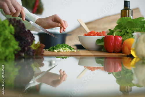 Closeup of human hands cooking vegetables salad in kitchen on the glass table with reflection