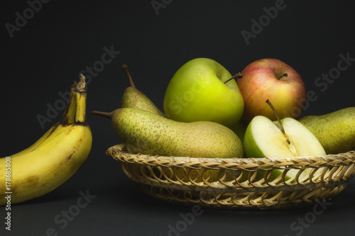 Still life with fruit basket, pears, apples and bananas isolated on gray