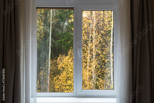 White window with sill and autumn landscape, interior with window in autumn day