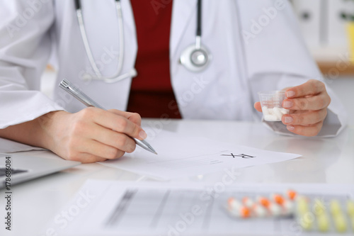 Female medicine doctor fills up  prescription form to patient closeup. Panacea and life save  prescribe treatment  legal drug store  contraception concept