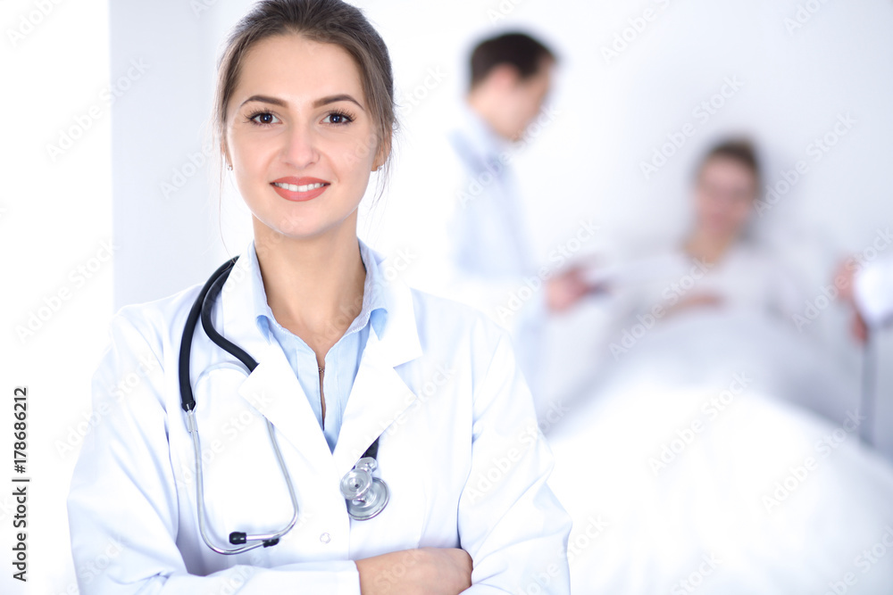Female doctor smiling on the background with patient in the bed Female doctor smiling on the background with patient in the bed