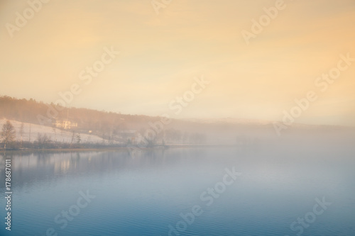 A beautiful  colorful misty morning in Norway at the lake. Tree reflections in the water. Misty autumn landscape. Calm nordic scenery.