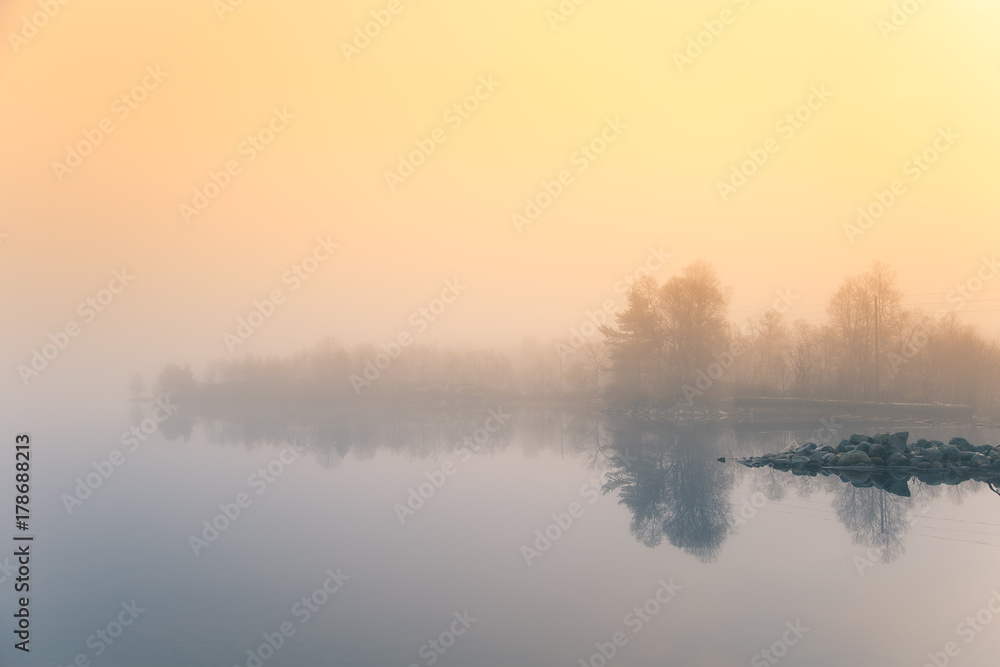 Fototapeta premium A beautiful morning scenery at the lake in Norway. Tranquil autumn landscape. Rock formation in a foreground. Colorful landscape with mist.