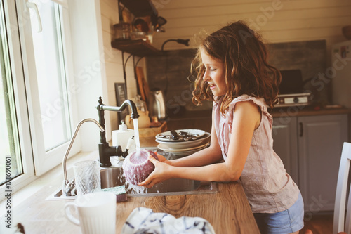 Bild auf Leinwand child girl helps mother at home and wash dishes in kitchen