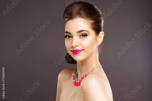 Portrait of Beautiful Brunette Winking Woman with Perfect Makeup and Hairstyle. Close Up Isolated on Gray Background