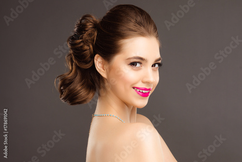 Portrait of Beautiful Brunette Winking Woman with Perfect Makeup and Hairstyle. Close Up Isolated on Gray Background