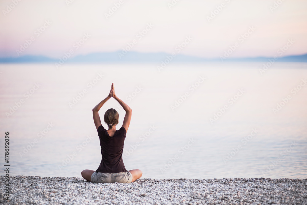Young woman practicing yoga near the sea. Harmony and meditation concept. Healthy lifestyle
