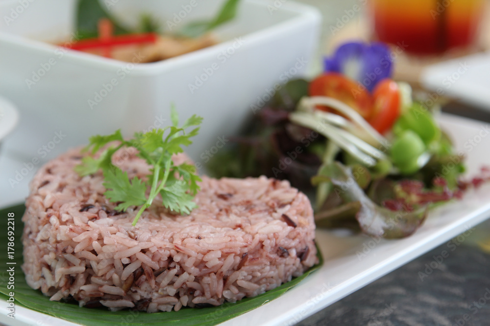 Thai cuisine, red steamed rice on banana leaf with coriander on topped. Thai cuisine, red steamed rice on banana leaf with coriander on topped.