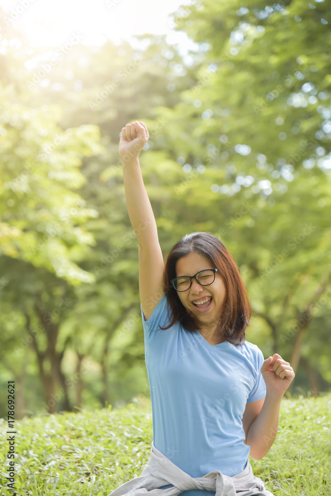 Asian woman celebrating with arm raised up.