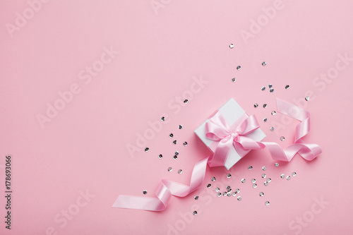 Gift or present box and sequins on pink table top view. Flat lay. Birthday, wedding or christmas concept. © juliasudnitskaya