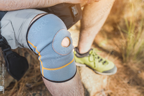 close up of knee support brace on leg of a traveler man during hiking outdoors in nature photo