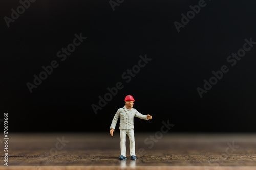Miniature people worker on wooden floor with black background ,construction concept