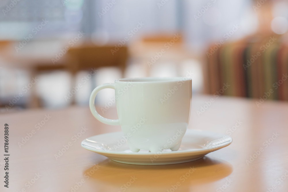 a white cup of tea or coffee on a wooden table in a Cafe close-up with copy space a white cup of tea or coffee on a wooden table in a Cafe close-up with copy space