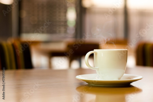 a white cup of tea or coffee on a wooden table in a Cafe close-up with copy space