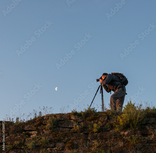 Photographer with camera on mountain peak
