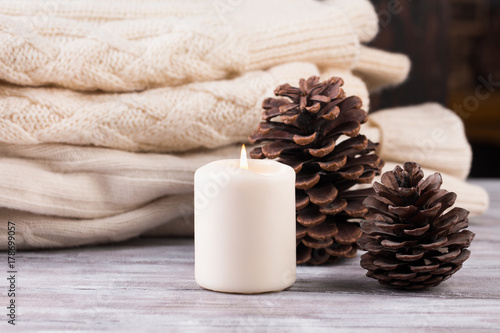 Christmas decoration. Pile of warm sweater, candle and cones.
