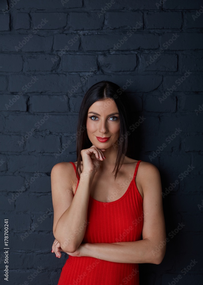 Young woman in red smiling against black wall Young woman in red smiling against black wall