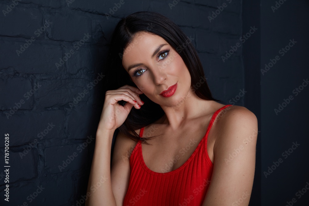 Young woman in red smiling against black wall Young woman in red smiling against black wall