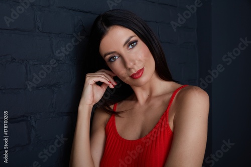 Young woman in red smiling against black wall