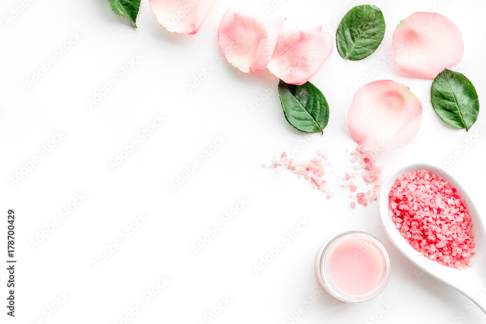 Pattern with rose oil cosmetics. Rose petals, spa salt on white background top view copyspace
