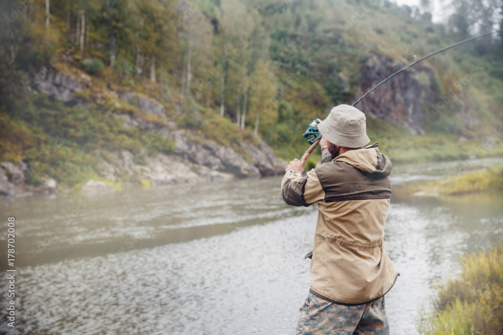 Fishing. The fisherman on a background of rocks throws the fishing rod into the water for catching fish. Concept rest, hobby Fishing. The fisherman on a background of rocks throws the fishing rod into the water for catching fish. Concept rest, hobby
