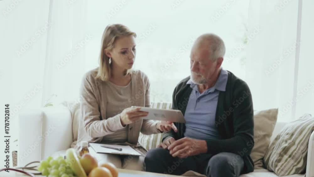 Health visitor and a senior man with tablet during home visit. Health visitor and a senior man with tablet during home visit.
