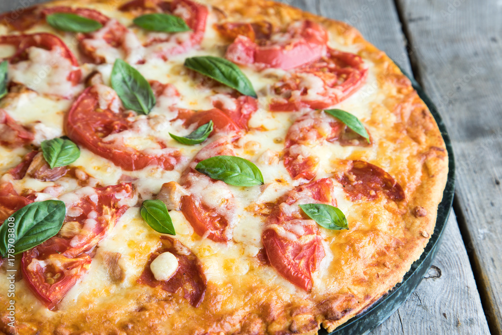 Hot Homemade Pepperoni Pizza on a rustic wooden table. Pizza with tomato, cheese and basil with copy space