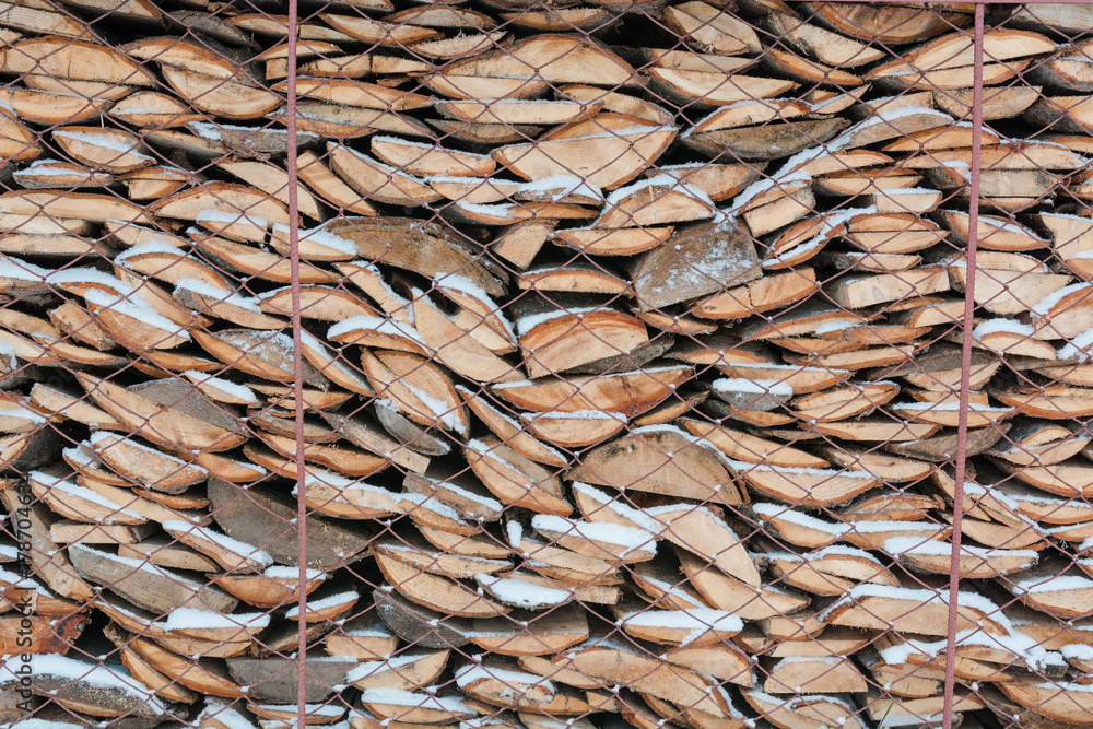 Firewood in a woodpile. Firewood under snow. Texture of firewood.