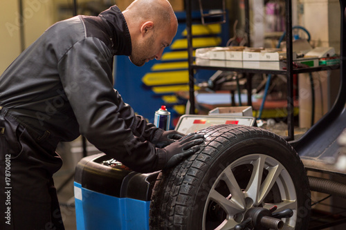 Fotografie auto mechanic balancing car wheel at workshop