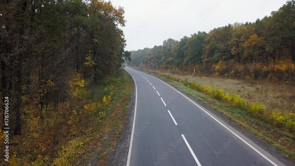 Aerial view of car on the road surrounded by autumn forest Aerial view of car on the road surrounded by autumn forest