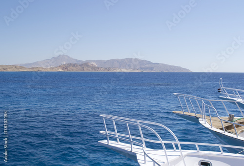 parts of yachts against a background of blue water and islands © alexmal