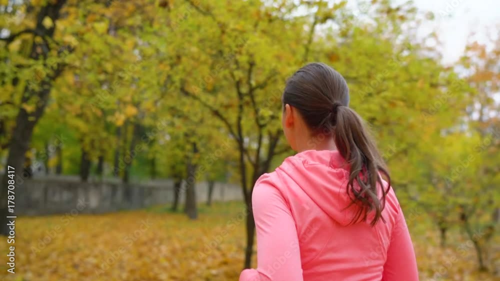 Close up of woman running through an autumn park at sunset Close up of woman running through an autumn park at sunset