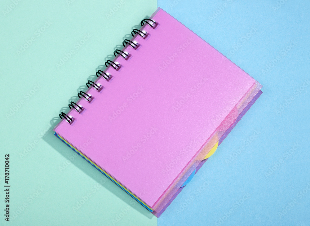 Notepad with pink cover on a colored background Notepad with pink cover on a colored background