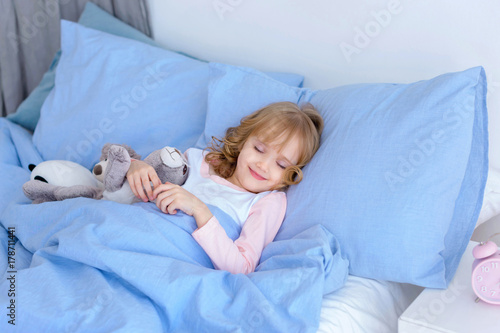 child, little girl sleeping in bed with toy rabbit 