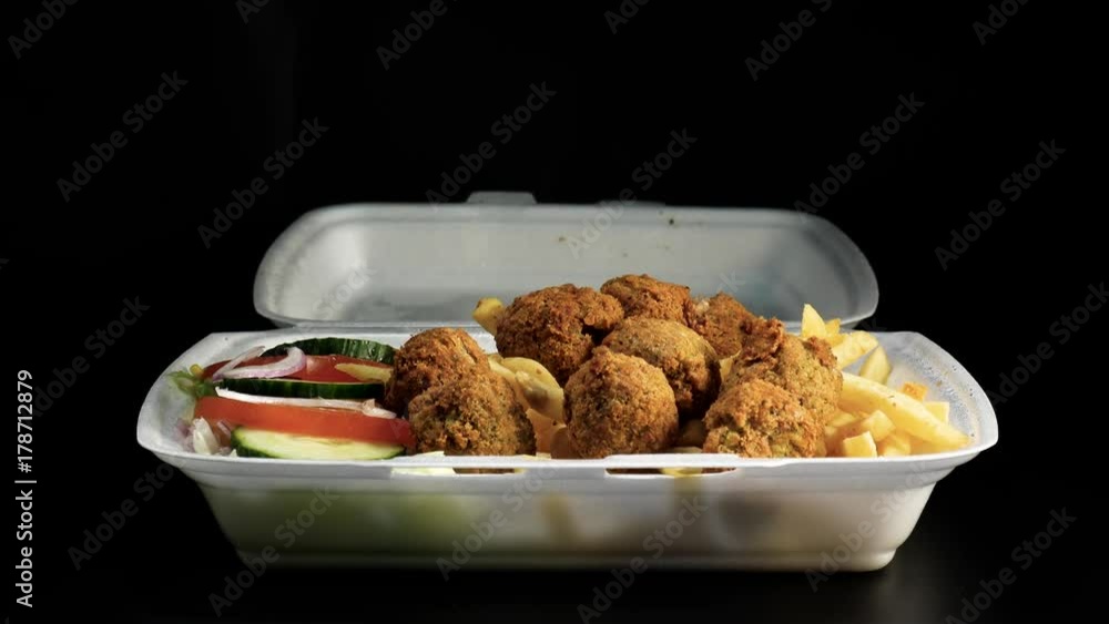 Fresh falafel and French fries with salad and hot sauce. Against black backgrou Fresh falafel and French fries with salad and hot sauce. Against black backgrou