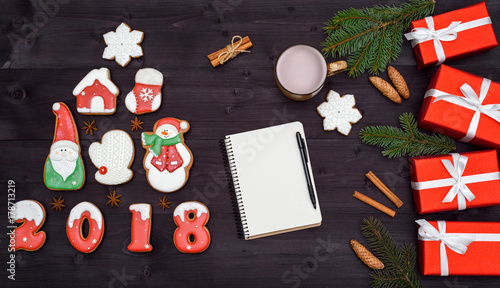 Top view of blank notebook on wooden background with xmas decorations, copy space. Christmas background with empty notebook, gingerbread cookies and hot cocoa, red gift boxes. Flat lay