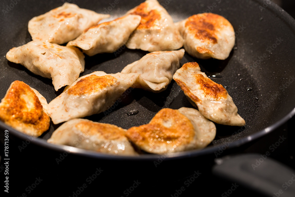 Traditional delicious Polish dumplings fried in a pan. Photography with shallow depth of field.