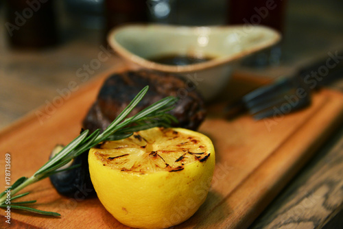 Grilled beef steak and half toasted lemon on a wooden board photo