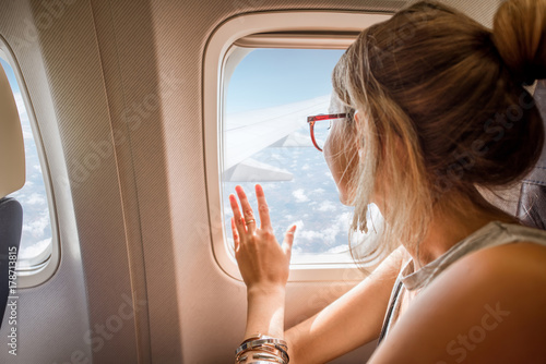 Young woman enjoying the view through the aircraft window sitting during the flight in the airplane photo