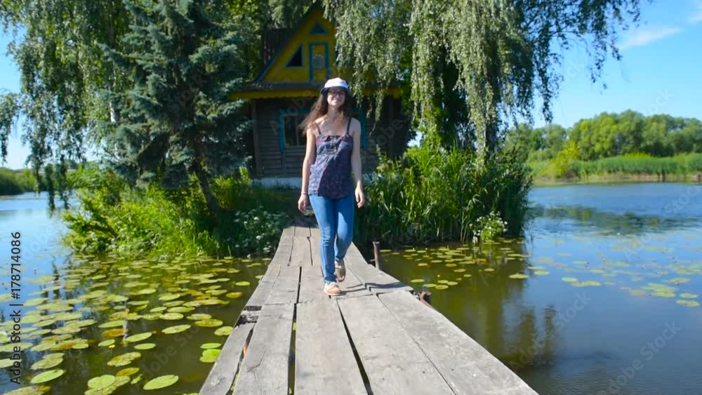 young female walking near the house on lake in countryside young female walking near the house on lake in countryside