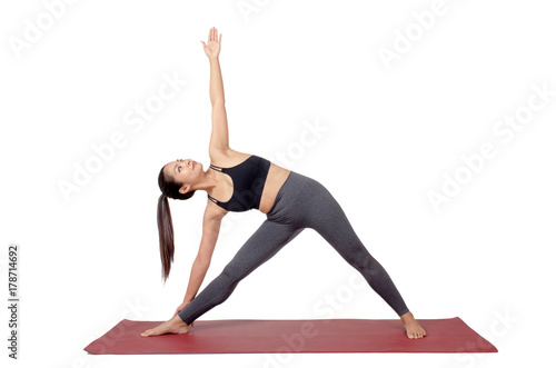 young asian woman doing yoga in Trikonasana or Triangle pose on mat isolated on white background, exercise fitness, sport training, healthy lifestyle concept