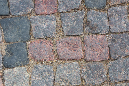 cobblestone pavement. Texture of cobblestone road close-up. Part of the road paved with red black granite.