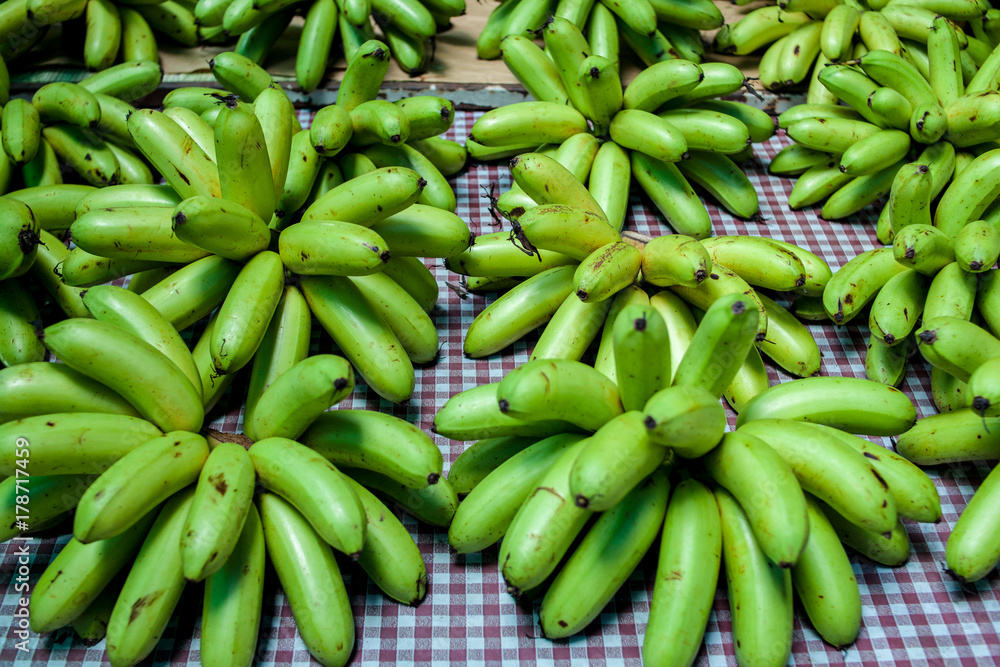 many green banana put for sale on the frabic in the Thailand market. Fruit sell in the market in the morning 