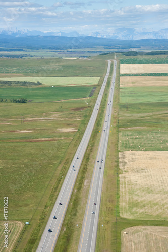 Aerial photo of a long road/highway leading into the horizon with mountains in the background.