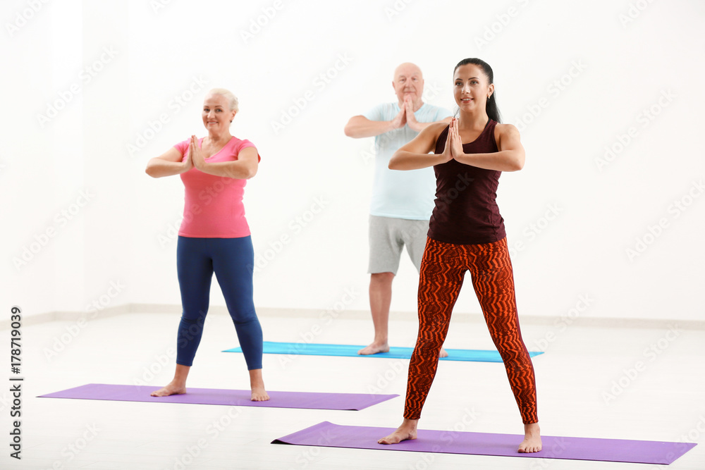 Naklejka premium Group of mature people at yoga lesson indoors